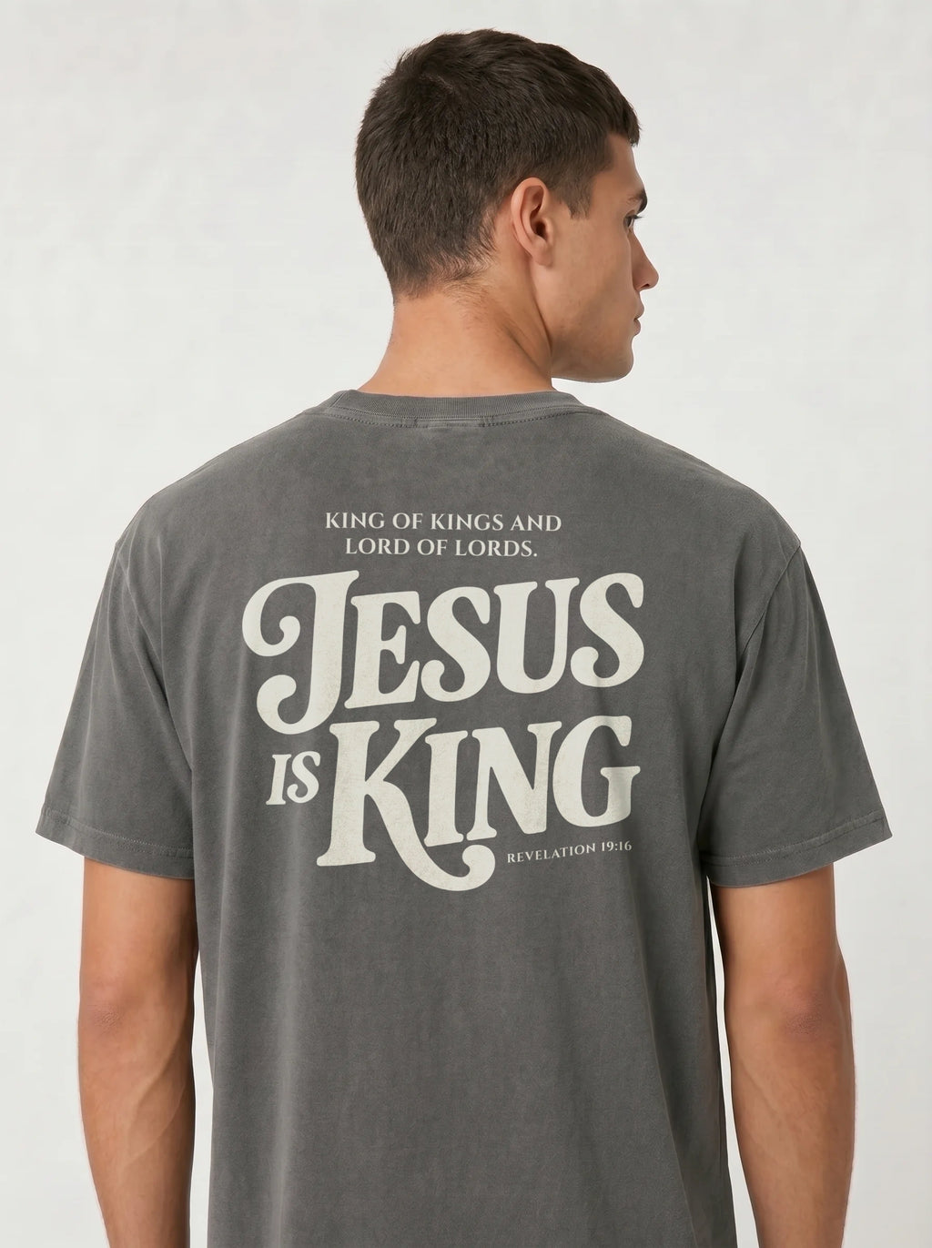 Person wearing a faded gray T-shirt with back text: “King of Kings and Lord of Lords. Jesus is King. Revelation 19:16.”
