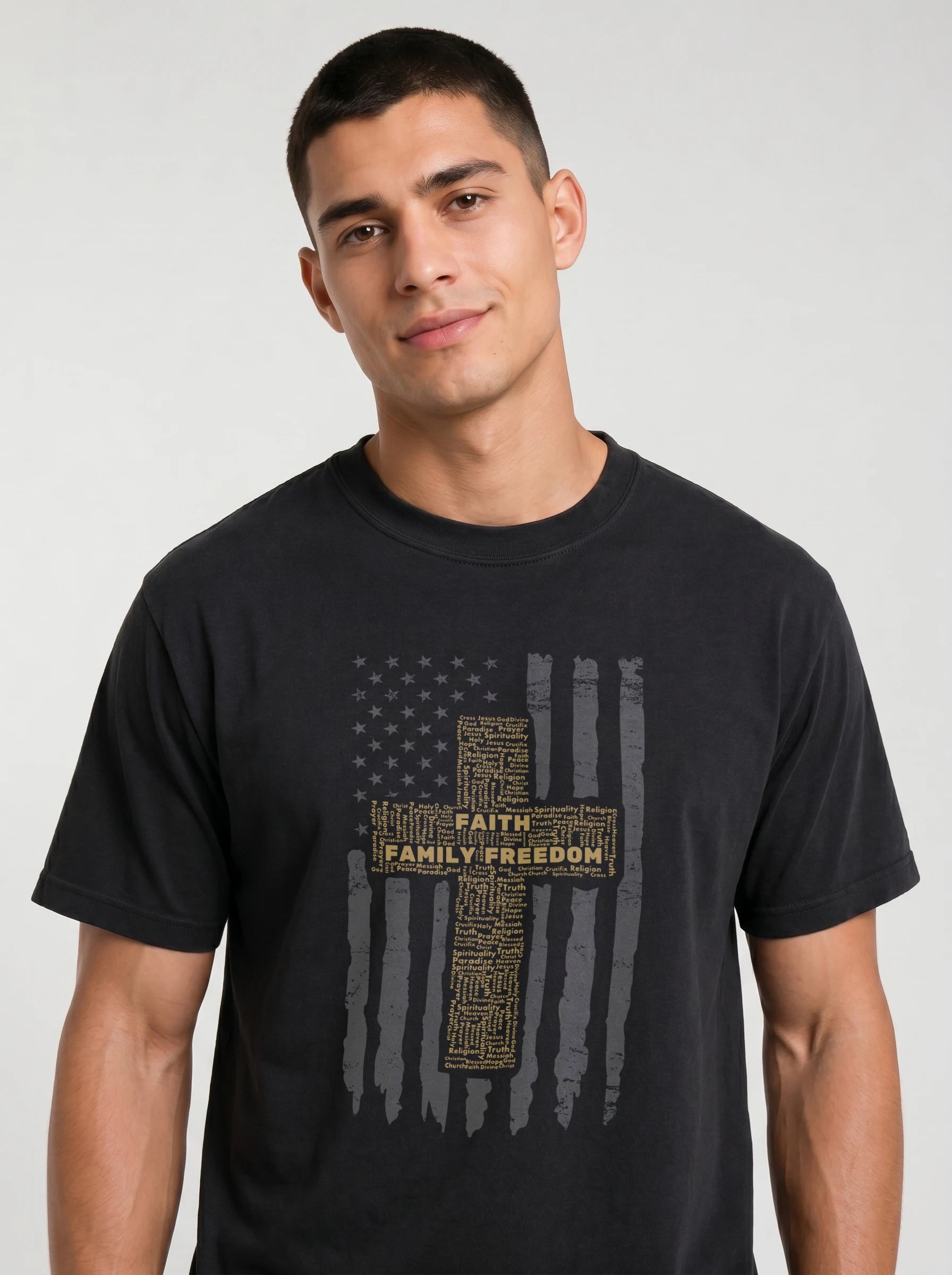 A man wearing a black crewneck t-shirt with distressed American flag graphic featuring a central cross and the words 'FAITH FAMILY FREEDOM' in gold, set against a plain light gray background.