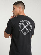 A man wearing a black t-shirt, viewed from the back. The shirt features a large white circular graphic on the back with the text 'IRON SHARPENS IRON' and 'PROVERBS 27:17' surrounding an illustration of two crossed nails.