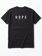 A black short-sleeve t-shirt shown from the back, featuring the word 'HOPE' printed in white capital letters with 'ROMANS 15:13' underneath, displayed on a clean white background.