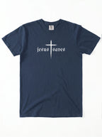 A navy blue short-sleeve t-shirt with a white graphic on the chest featuring a cross and the gothic text 'jesus saves', displayed flat against a white background.
