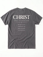 Back of a gray T-shirt laid flat with “Christ The Standard,” a small cross, and “Humility, Strength, Discipline, Sacrifice.”