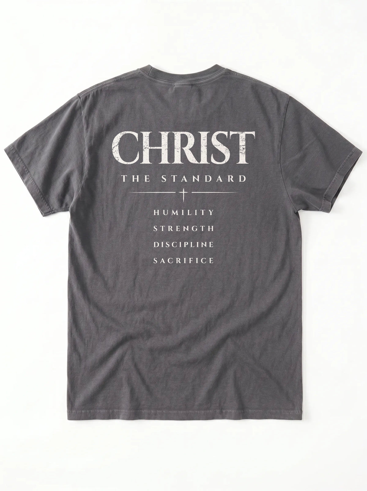 Back of a gray T-shirt laid flat with “Christ The Standard,” a small cross, and “Humility, Strength, Discipline, Sacrifice.”