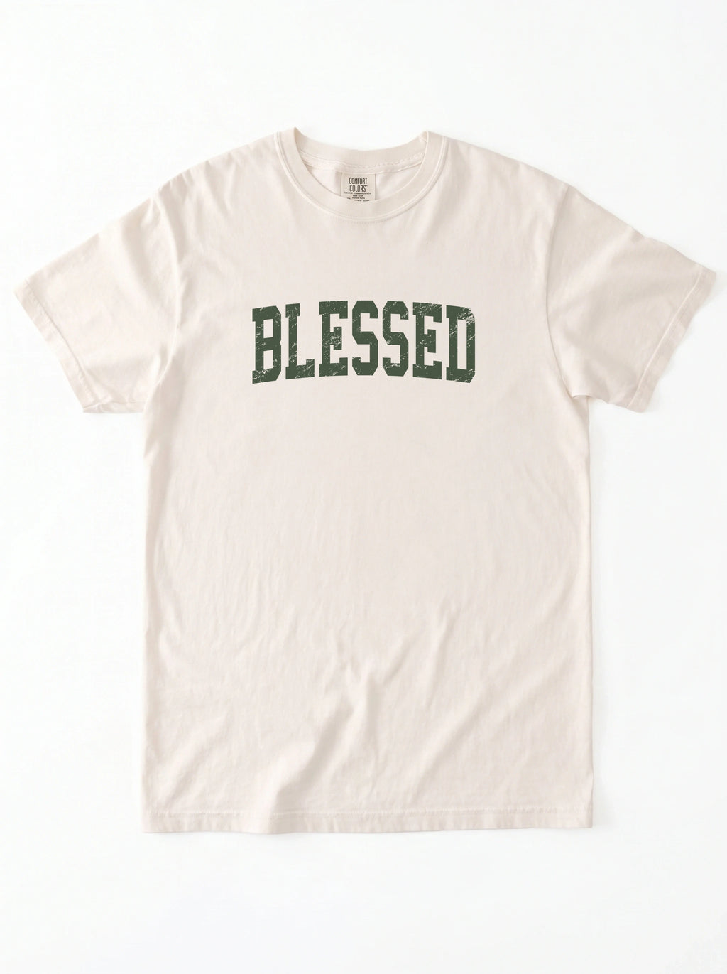 A light beige crewneck t-shirt with the word 'BLESSED' printed across the chest in a dark green collegiate-style font, laid flat against a white background.