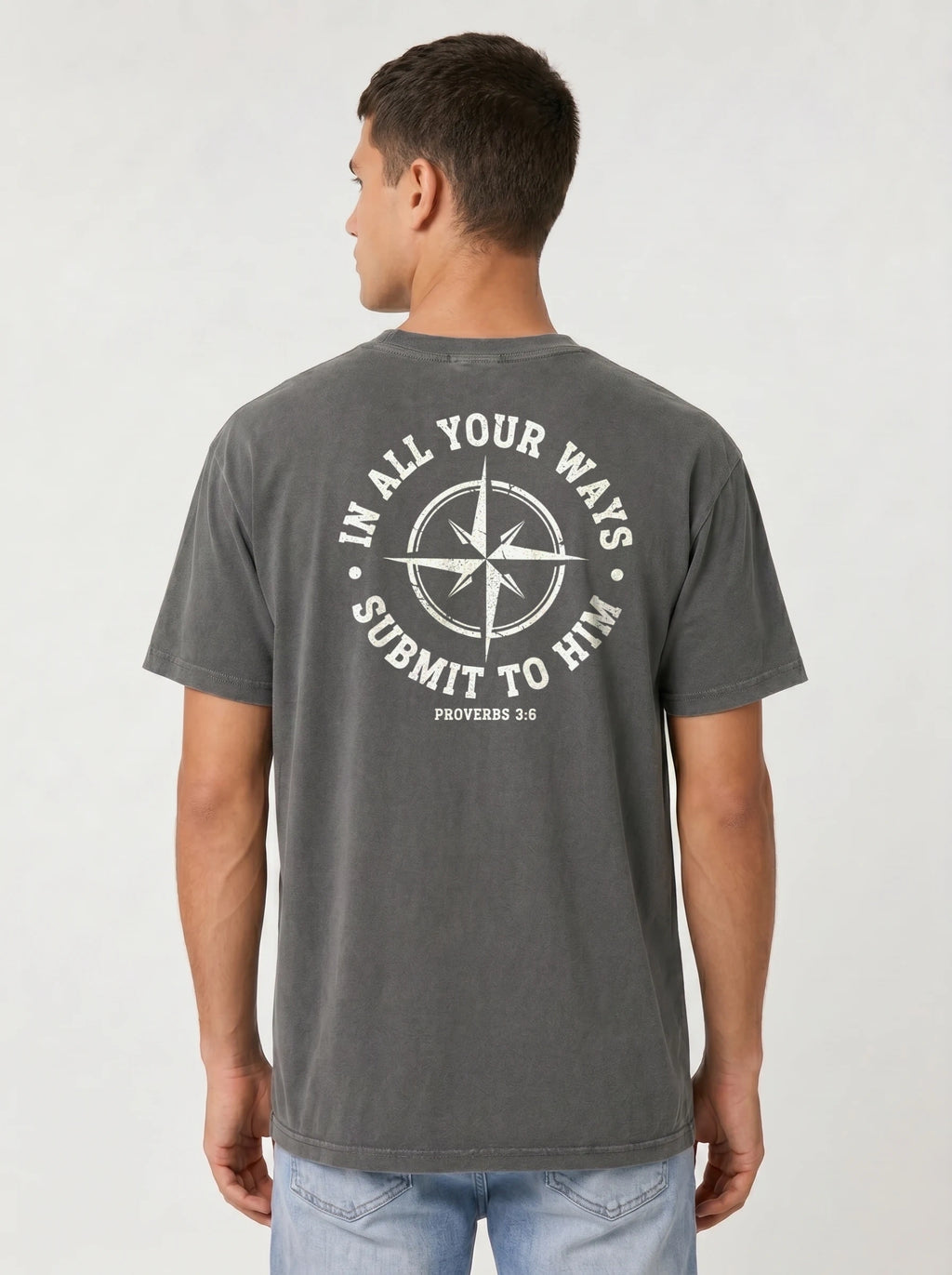 A man viewed from the back wearing a dark gray t-shirt with a white circular compass graphic and the text white circular graphic print on the back that reads 'IN ALL YOUR WAYS SUBMIT TO HIM' and 'PROVERBS 3:6'.