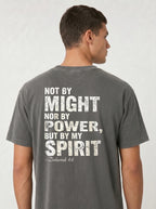 A man viewed from the back wearing a dark gray t-shirt with a distressed white typographic print that reads 'NOT BY MIGHT NOR BY POWER, BUT BY MY SPIRIT - Zechariah 4:6'.