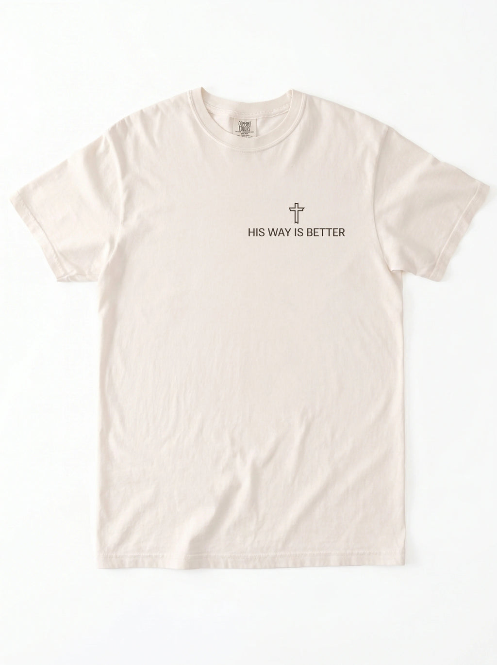 A light beige crewneck t-shirt with a small black graphic on the left chest featuring a cross and the text 'HIS WAY IS BETTER'.