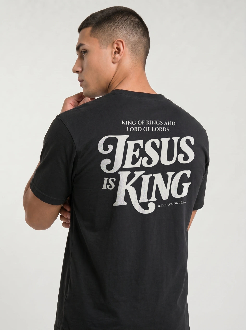 Person wearing a black T-shirt with back text: “King of Kings and Lord of Lords. Jesus is King. Revelation 19:16.”
