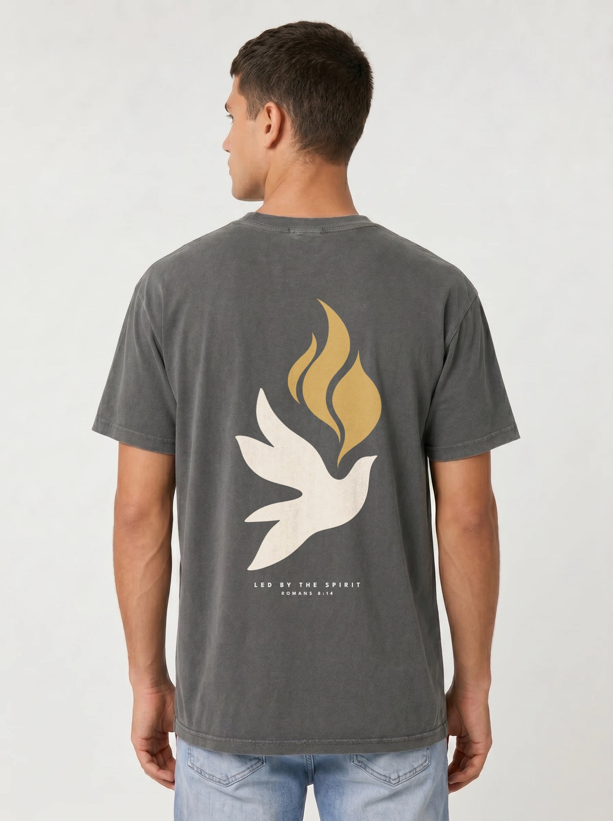 Person wearing a faded charcoal T-shirt with a large white dove, gold flames, and “LED BY THE SPIRIT ROMANS 8:14” on the back.
