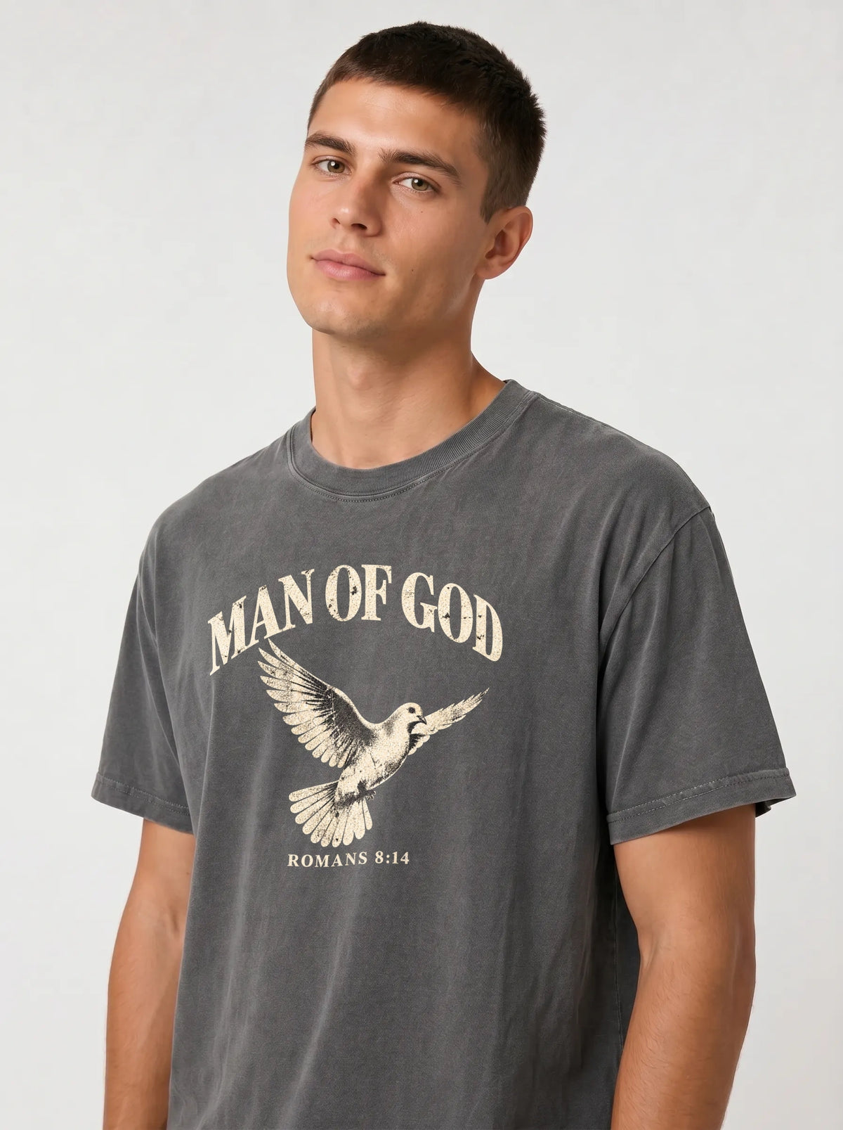 Close-up of a person wearing a charcoal T-shirt with a flying dove and the text “Man of God” and “Romans 8:14.”