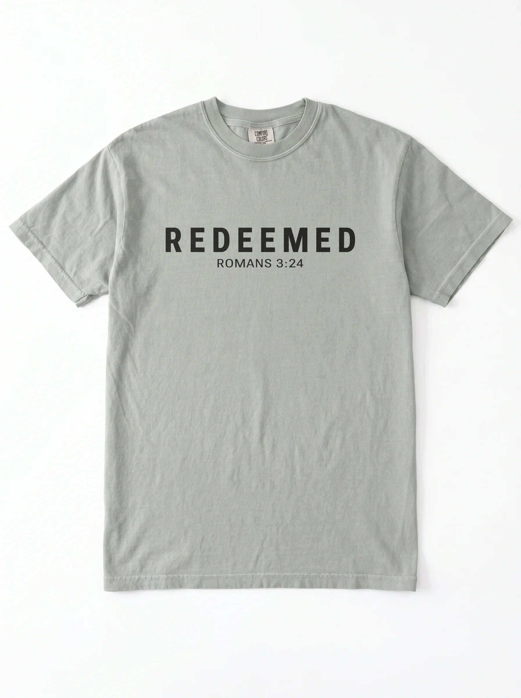 A light gray short-sleeve crewneck t-shirt with 'REDEEMED ROMANS 3:24' printed in black across the chest, displayed flat against a white background.