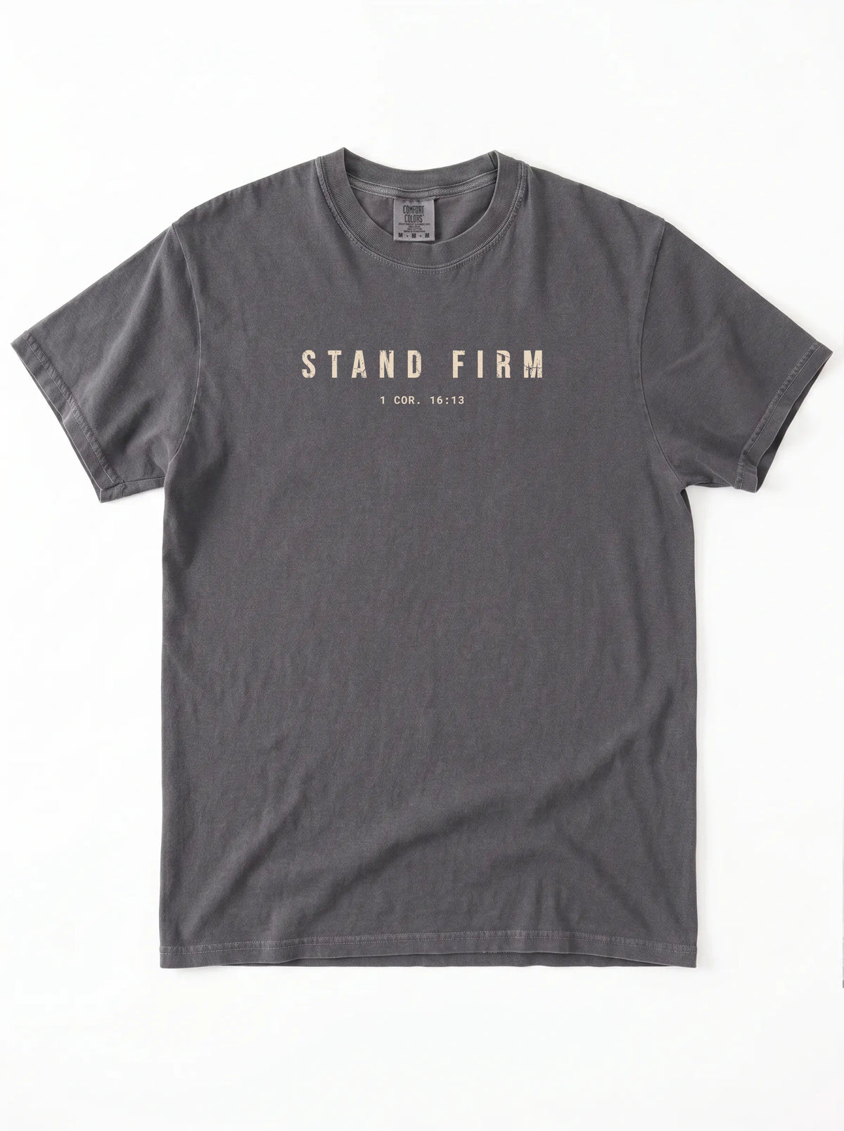 Faded gray T-shirt laid flat with distressed beige text reading “Stand Firm” and “1 Cor. 16:13.”