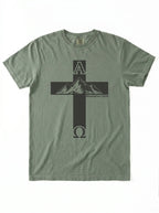 An olive green short-sleeve t-shirt with a black graphic of a cross containing a mountain peak and the Greek letters Alpha and Omega, on a white background.