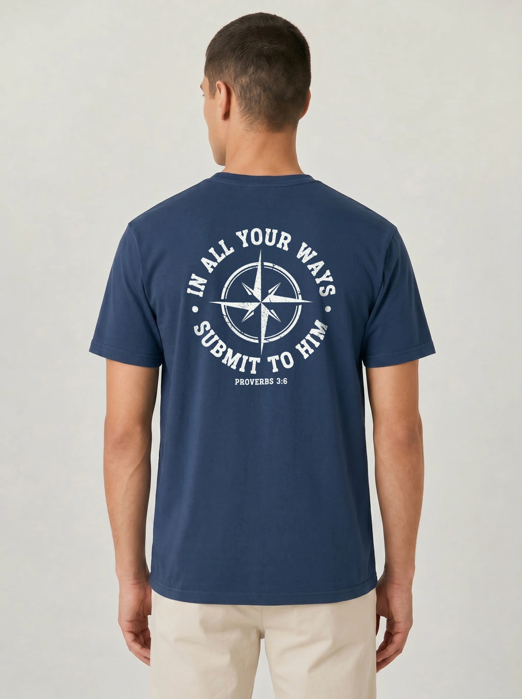 A man viewed from the back wearing a navy blue t-shirt with a white circular graphic on the back that reads 'IN ALL YOUR WAYS SUBMIT TO HIM' and 'PROVERBS 3:6'.