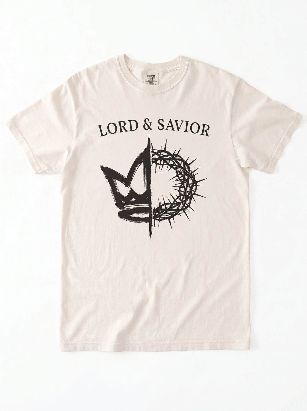 An off-white short-sleeve t-shirt with a black graphic print on the front. The graphic features the text 'LORD & SAVIOR' above a crown of thorns split vertically, with a cross and a stylized heart on each side.