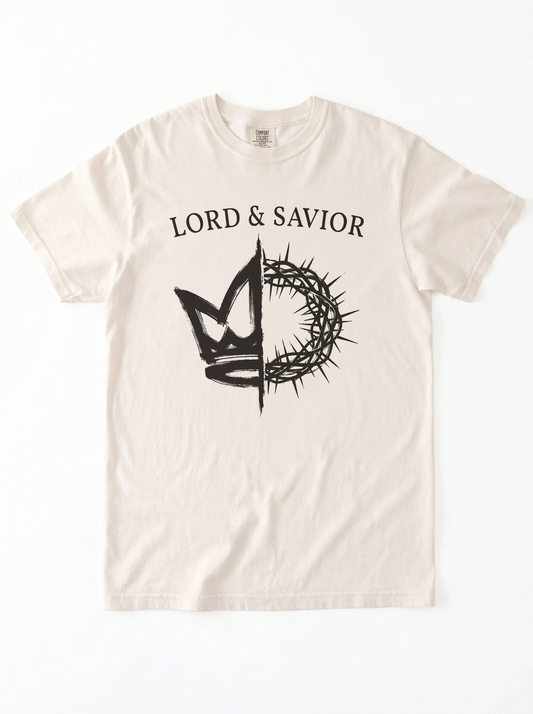An off-white short-sleeve t-shirt with a black graphic print on the front. The graphic features the text 'LORD & SAVIOR' above a crown of thorns split vertically, with a cross and a stylized heart on each side.