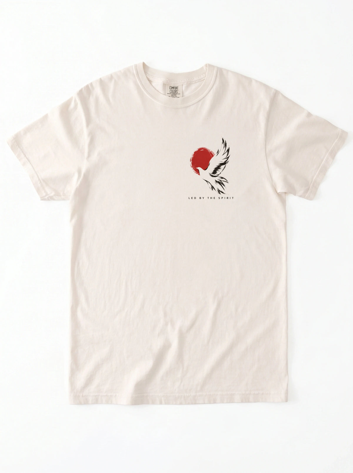 Cream T-shirt laid flat with a black-and-white flying bird against a red circle and “LED BY THE SPIRIT” on the chest.