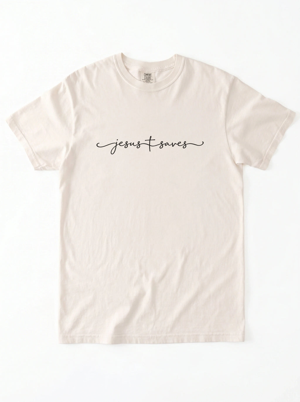 Cream T-shirt laid flat with black script reading “Jesus Saves,” with a cross incorporated into the lettering.