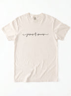 Cream T-shirt laid flat with black script reading “Jesus Saves,” with a cross incorporated into the lettering.