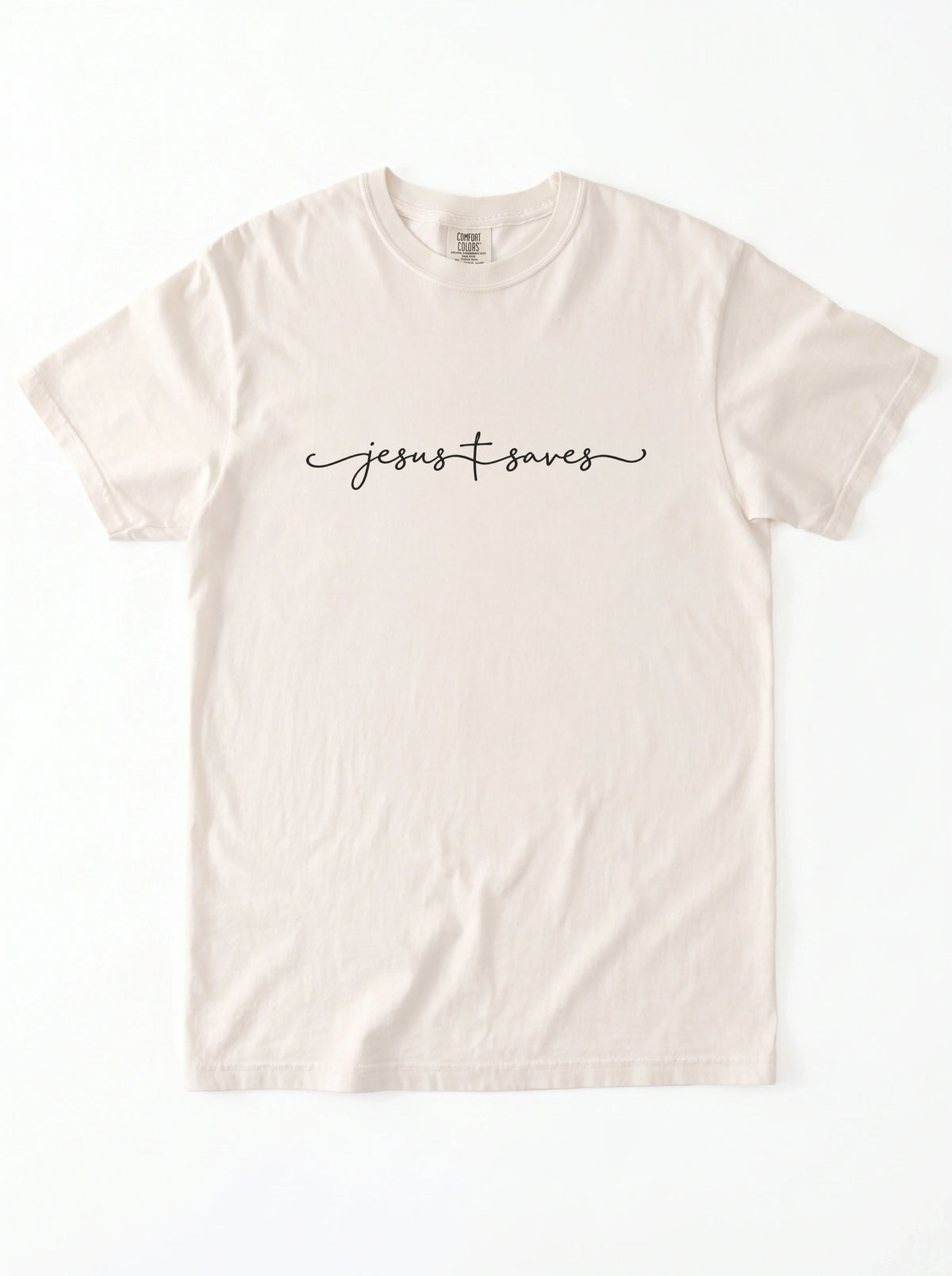 Cream T-shirt laid flat with black script reading “Jesus Saves,” with a cross incorporated into the lettering.
