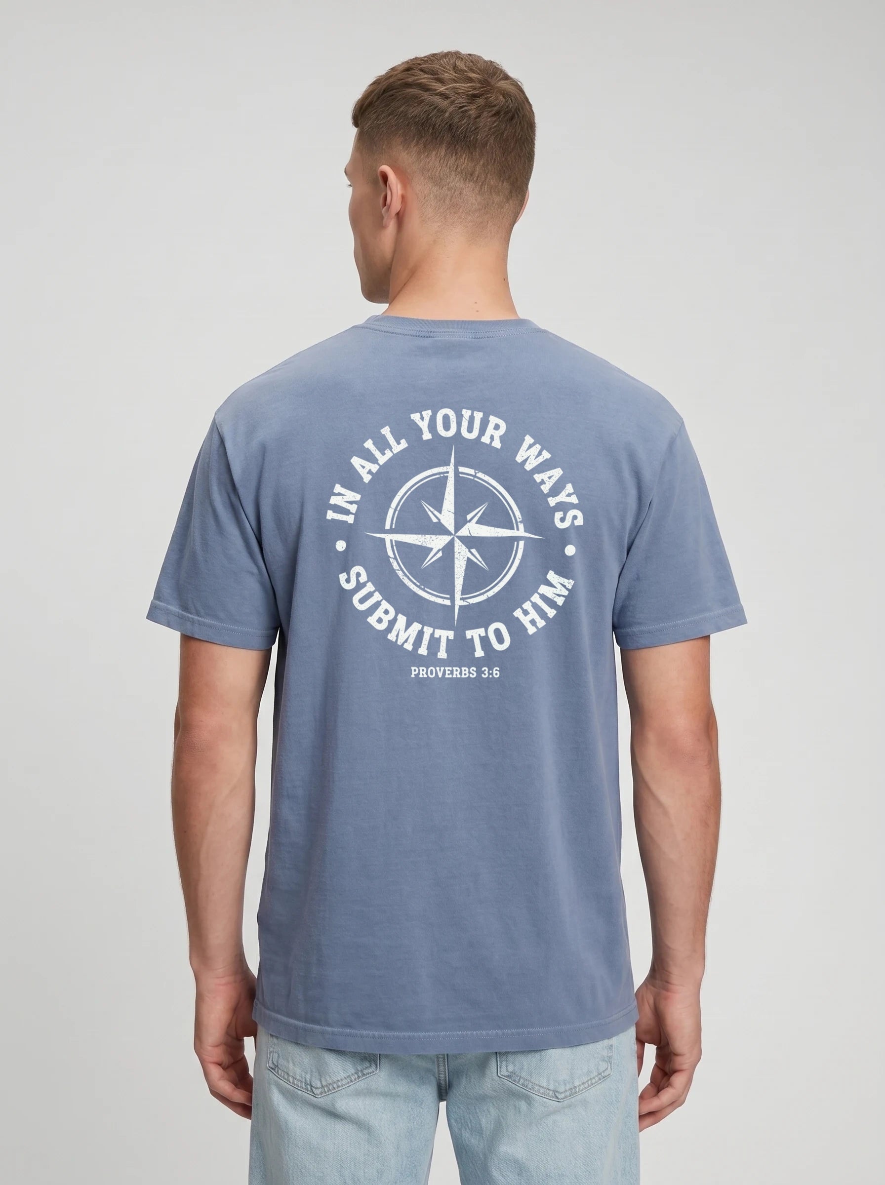 A man viewed from the back wearing a slate blue t-shirt with a white circular graphic on the back that reads 'IN ALL YOUR WAYS SUBMIT TO HIM' and 'PROVERBS 3:6'.