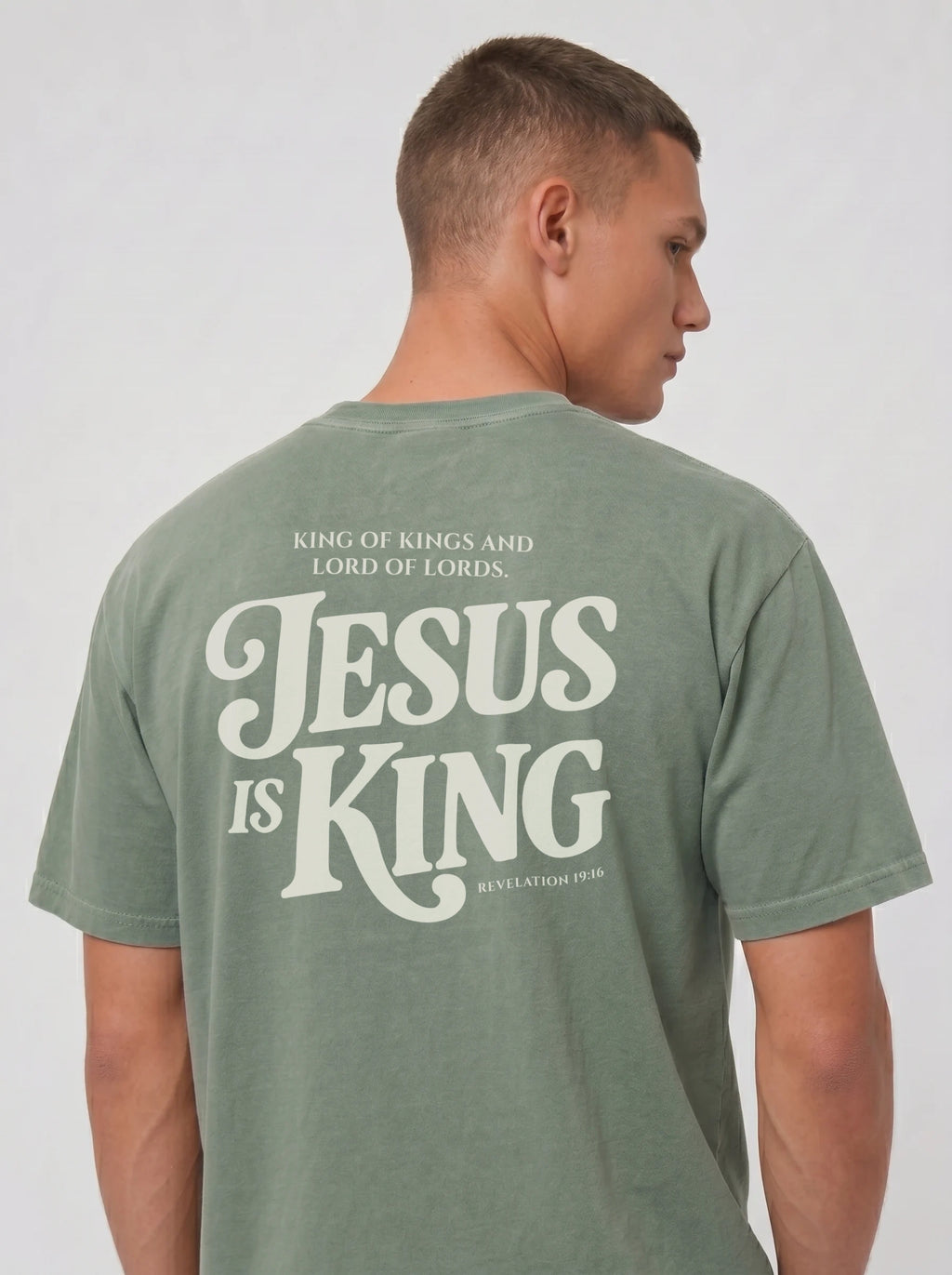 Person wearing a faded green T-shirt with back text: “King of Kings and Lord of Lords. Jesus is King. Revelation 19:16.”
