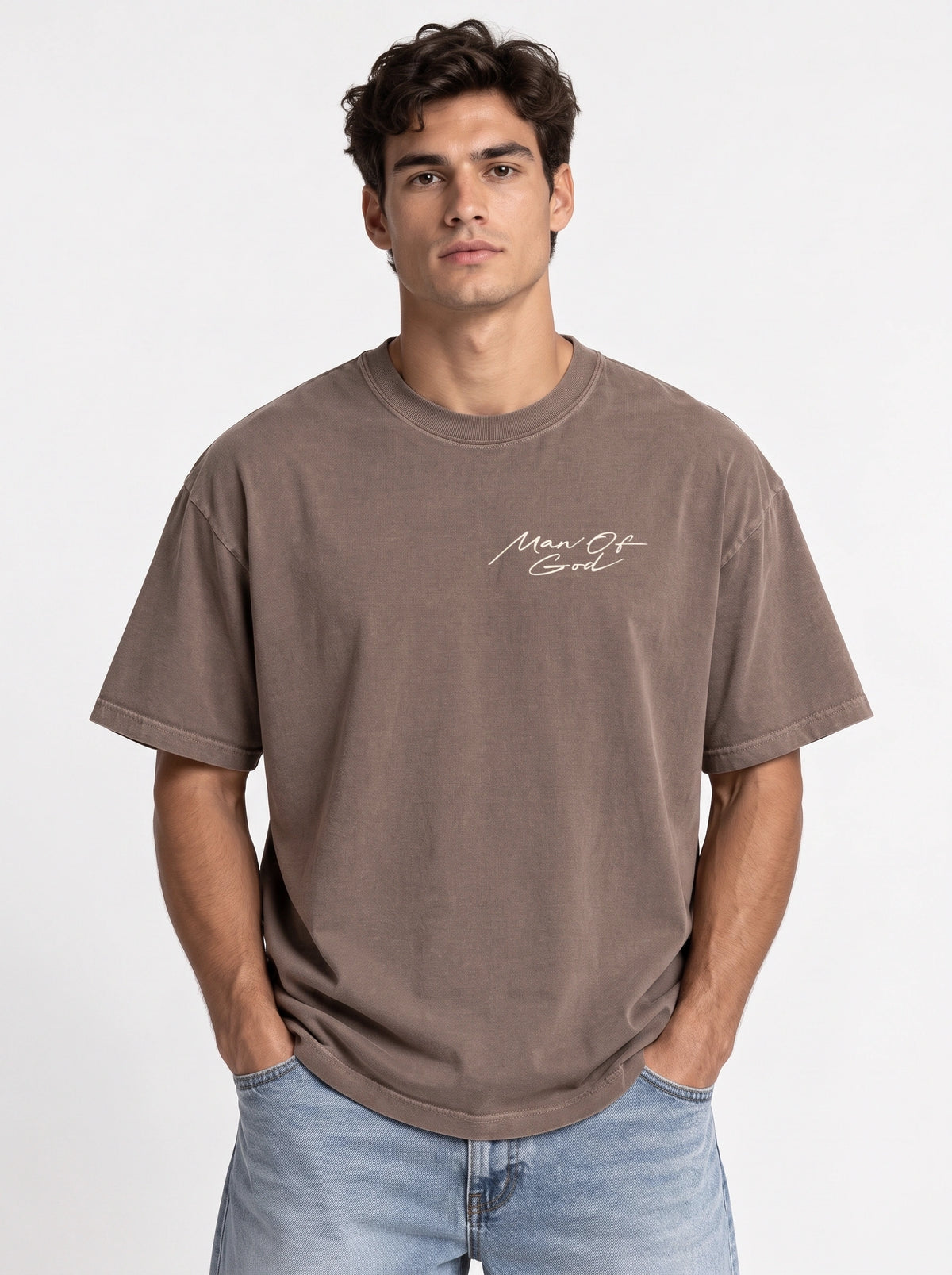 Person wearing a washed brown T-shirt with a small white script chest graphic reading “Man Of God.”