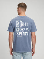 A man viewed from the back wearing a slate blue t-shirt with a distressed white graphic quote on the back reading 'NOT BY MIGHT NOR BY POWER, BUT BY MY SPIRIT -Zechariah 4:6'.