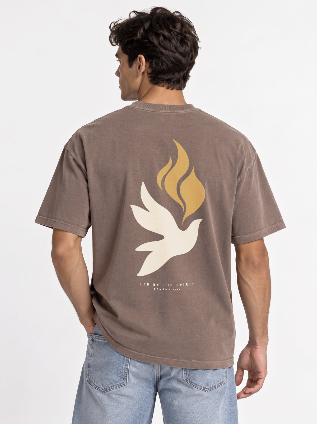 Person wearing a faded brown T-shirt with a large white dove, gold flames, and “LED BY THE SPIRIT ROMANS 8:14” on the back.