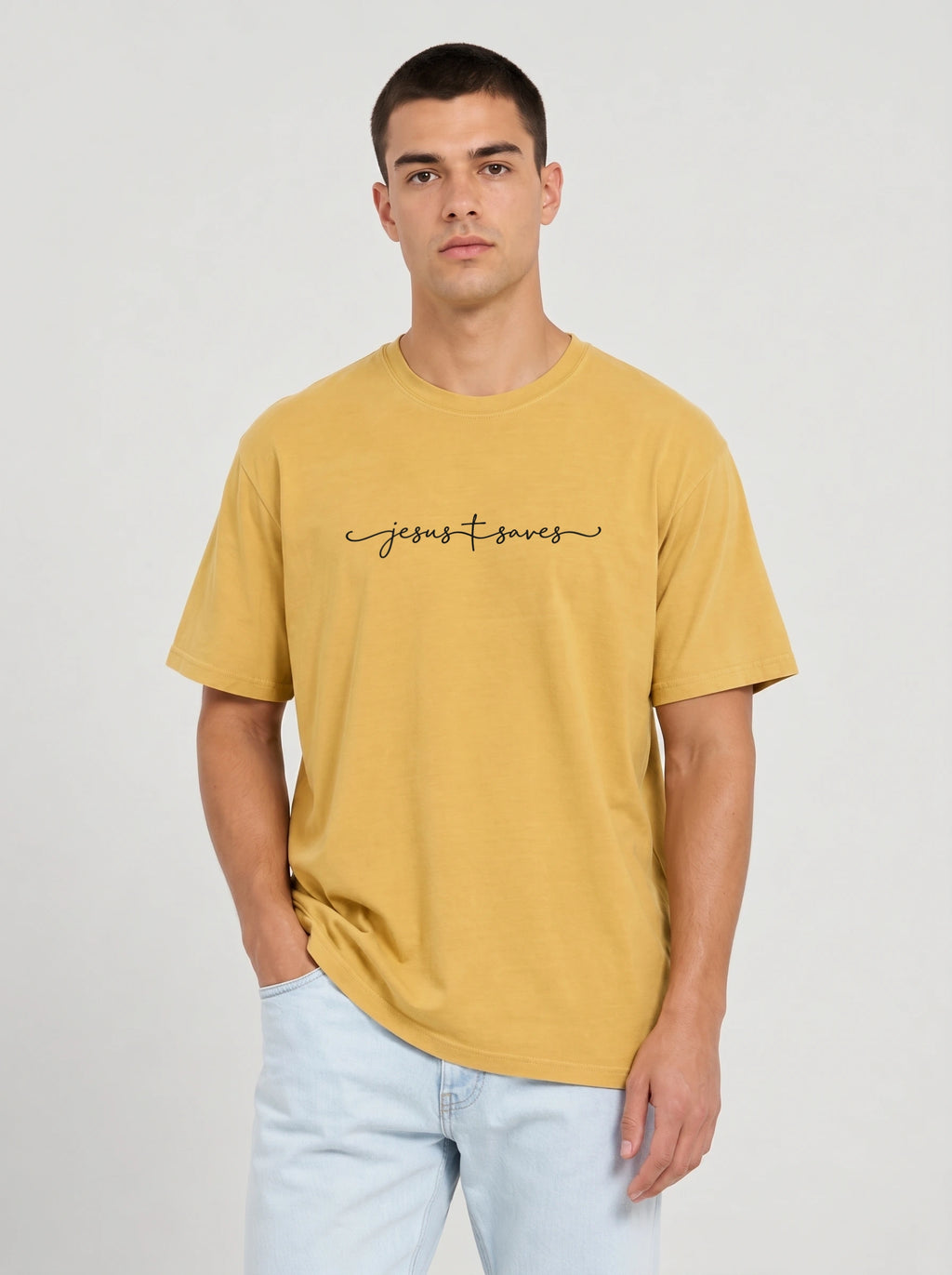 Person wearing a mustard yellow T-shirt with black script reading “Jesus Saves,” with a cross incorporated into the lettering.
