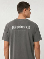 A man viewed from the back wearing a dark gray t-shirt with 'Philippians 4:13' printed in white gothic font across the upper back.