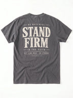 A dark gray crewneck t-shirt shown from the back, featuring a distressed white graphic print with the words 'STAND FIRM' and smaller inspirational text.