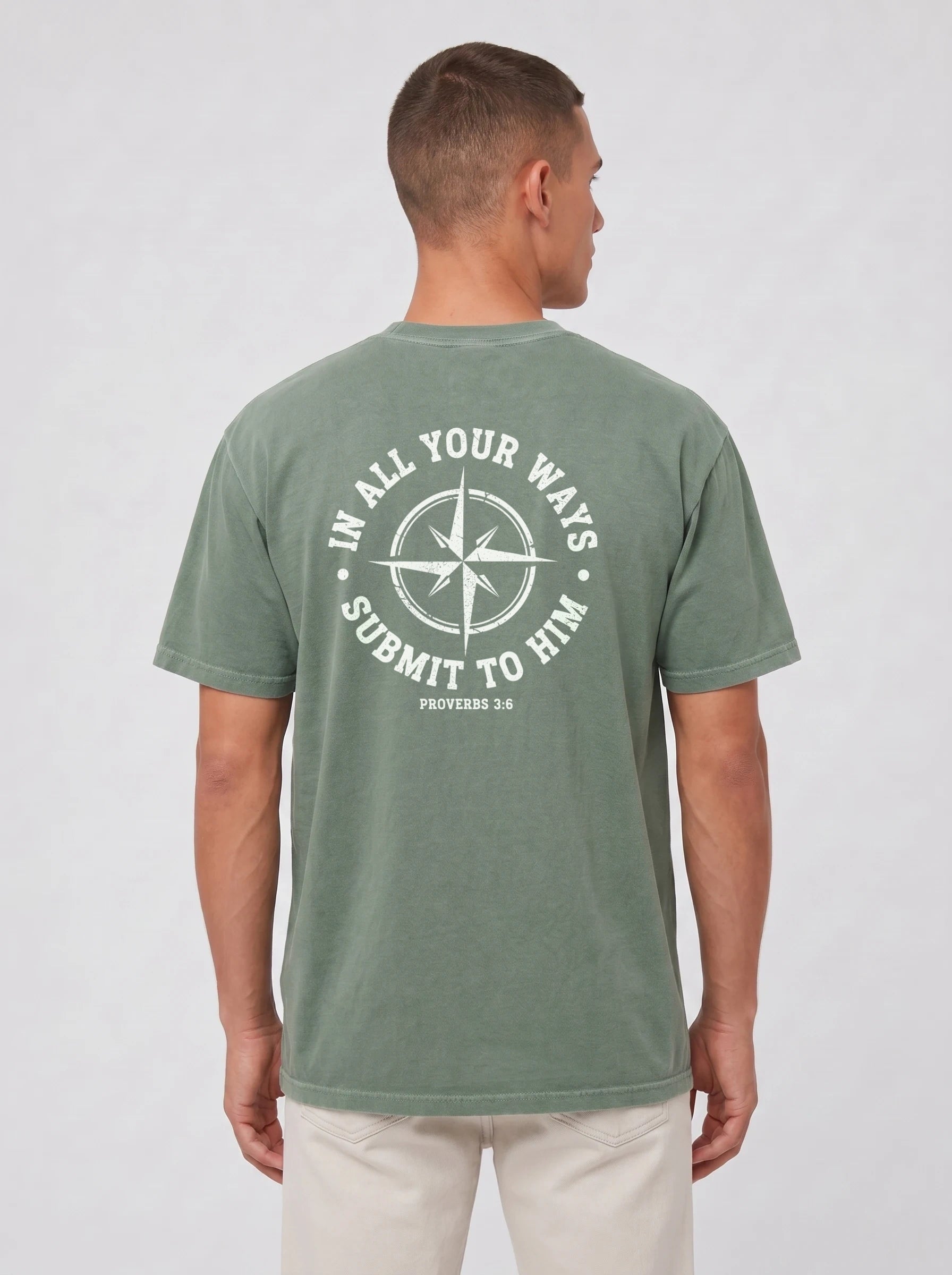 A man viewed from the back wearing a heathered sage green t-shirt with a white graphic print on the back featuring a compass rose and the text 'IN ALL YOUR WAYS SUBMIT TO HIM PROVERBS 3:6'.