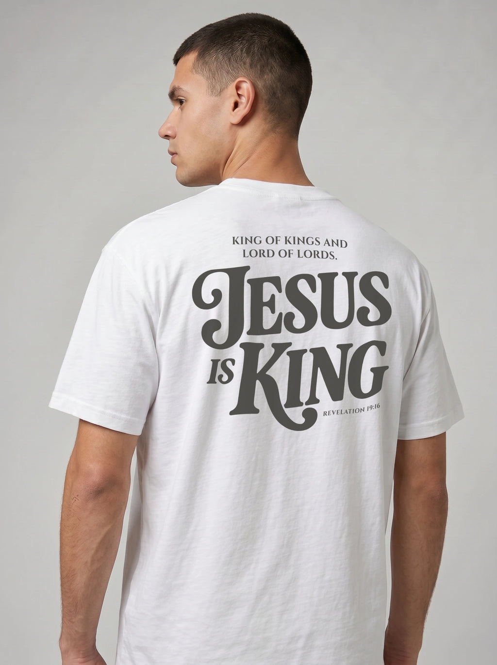 Person wearing a white T-shirt with dark back text: “King of Kings and Lord of Lords. Jesus is King. Revelation 19:16.”