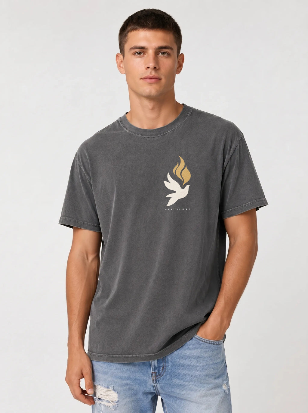 Person wearing a faded charcoal T-shirt with a small white dove, gold flames, and “LED BY THE SPIRIT” on the chest.