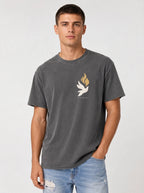 Person wearing a faded charcoal T-shirt with a small white dove, gold flames, and “LED BY THE SPIRIT” on the chest.
