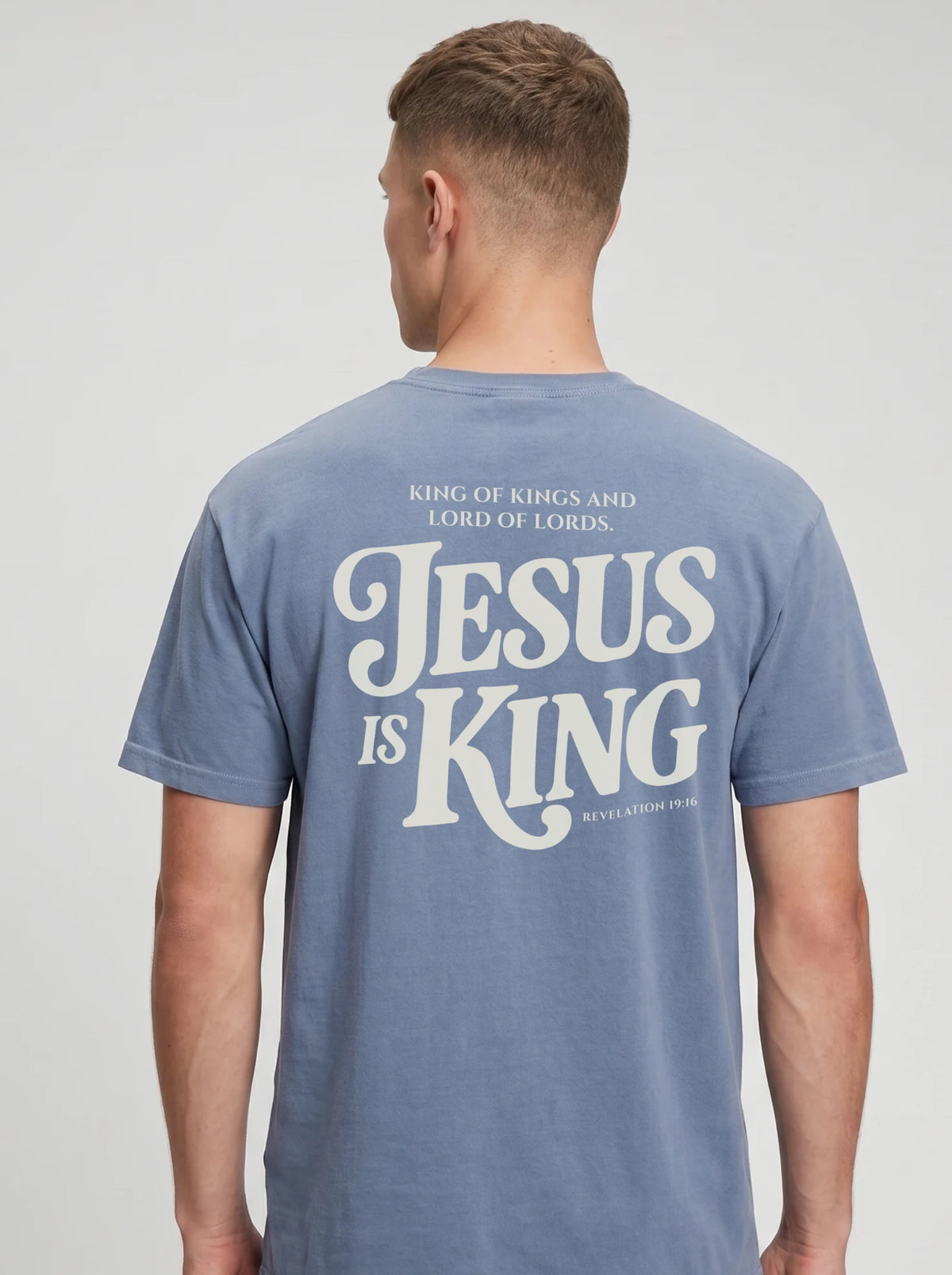 Person wearing a faded light blue T-shirt with back text: “King of Kings and Lord of Lords. Jesus is King. Revelation 19:16.”