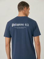 A man viewed from the back wearing a navy blue t-shirt with 'Philippians 4:13' printed in white gothic font across the upper back.