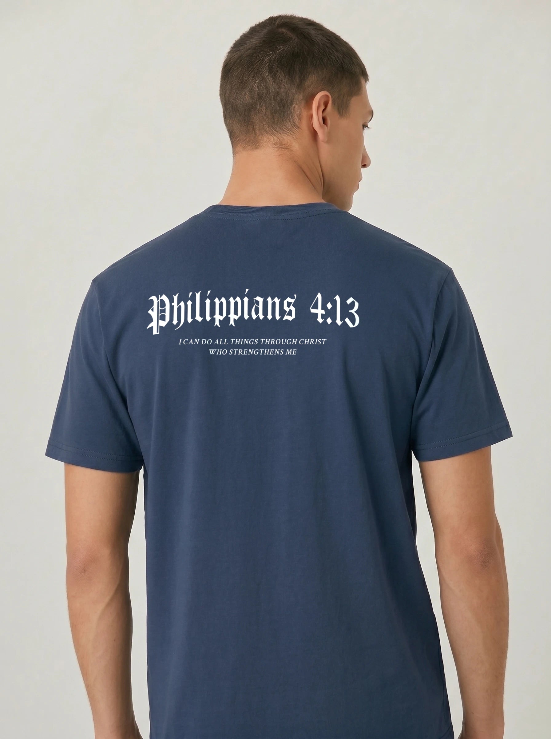 A man viewed from the back wearing a navy blue t-shirt with 'Philippians 4:13' printed in white gothic font across the upper back.