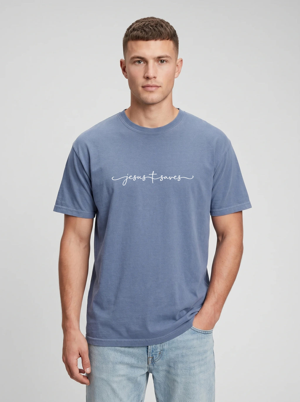 Person wearing a muted blue T-shirt with white script reading “Jesus Saves,” with a cross incorporated into the lettering.