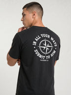 A man wearing a black t-shirt, viewed from the back. The shirt features a large white graphic print on the back with a compass rose and the text 'IN ALL YOUR WAYS SUBMIT TO HIM PROVERBS 3:6'.