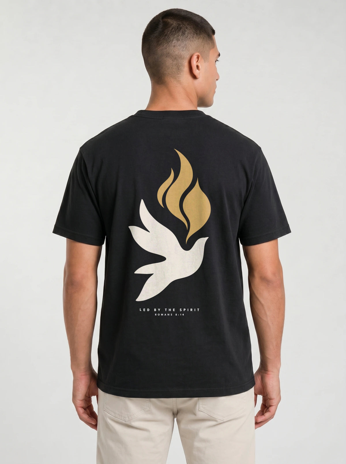 Person wearing a black T-shirt with a large white dove, gold flames, and “LED BY THE SPIRIT ROMANS 8:14” on the back.