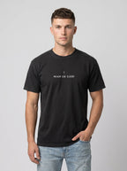 Person wearing a black T-shirt with a small cross above the text “Man of God.”