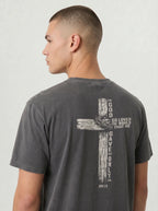 A man shown from the back wearing a dark gray t-shirt with a large distressed graphic on the back featuring a cross, a wreath, and white text reading 'GOD SO LOVED THE WORLD THAT HE GAVE ONLY ME'.