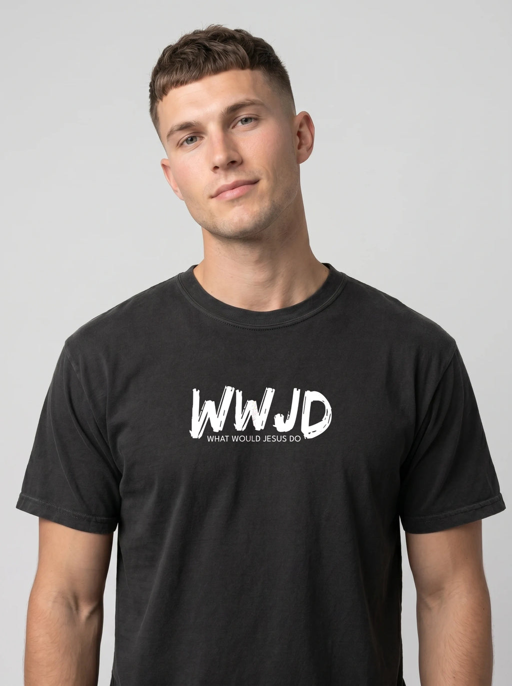 A man wearing a black crewneck t-shirt with a white graphic print on the chest that reads 'WWJD WHAT WOULD JESUS DO', photographed against a solid light gray background.