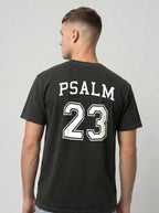 Side view of man wearing black garment-dyed t-shirt with Psalm 23 varsity print on the back