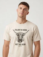 A man wearing a light beige crewneck t-shirt with a black graphic of a highland cow and the text 'FOLLOW THE WORD NOT THE HERD' and 'Isaiah 8:11-13'.