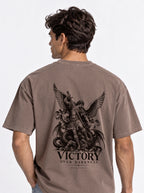 Brown T-shirt with a winged warrior defeating a dragon and the text “VICTORY OVER DARKNESS” and “REVELATION 12.”