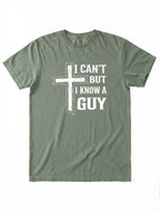 An olive green short-sleeve t-shirt with a white graphic print on the front featuring a distressed cross and the text 'I CAN'T BUT I KNOW A GUY'.