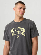 A man wearing a dark gray crewneck t-shirt with 'GOD OVER ALL THINGS' and a dove graphic printed in a light cream color on the chest, set against a plain light gray background.